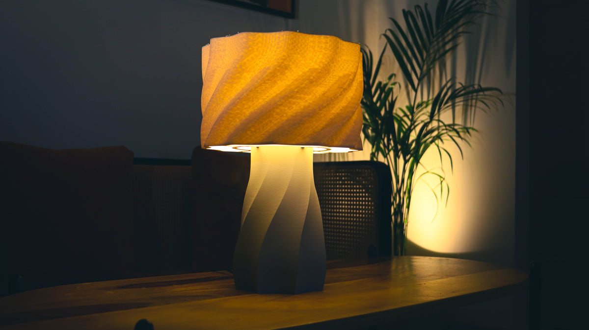 Aurelia Lamp illuminated warmly, showing twisted spiral base and ribbed shade