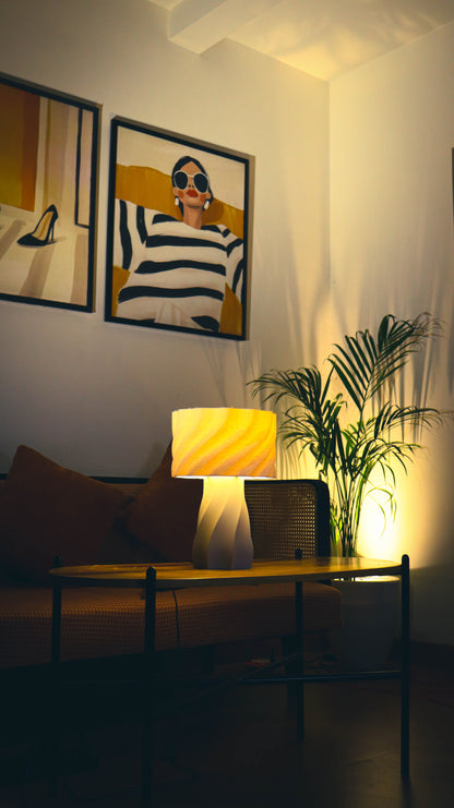 Aurelia Lamp - twisted white base with warm amber lit shade in cozy setting