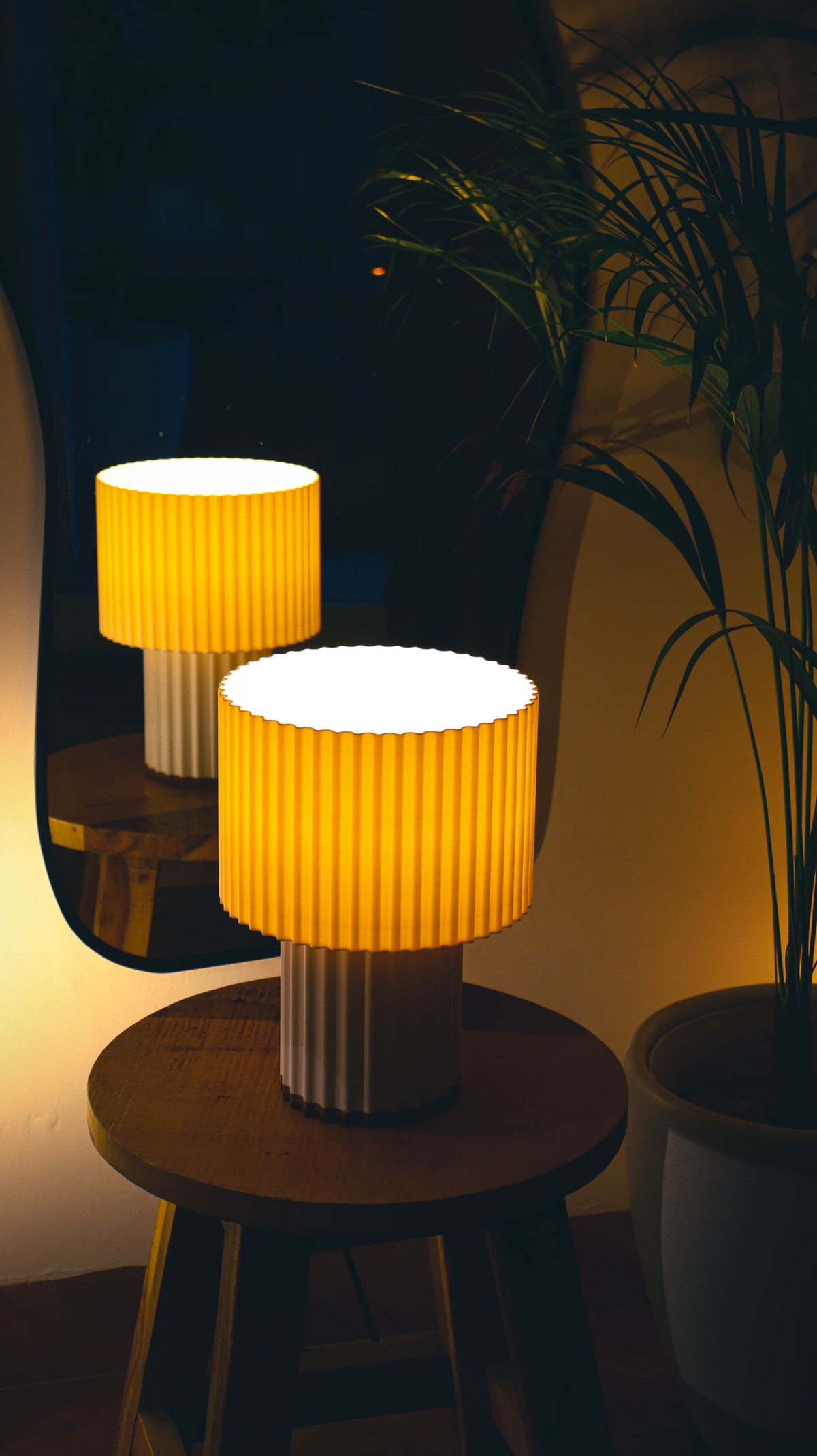 Fluted table lamp with tiered cylindrical shades, warm glow, wooden stool