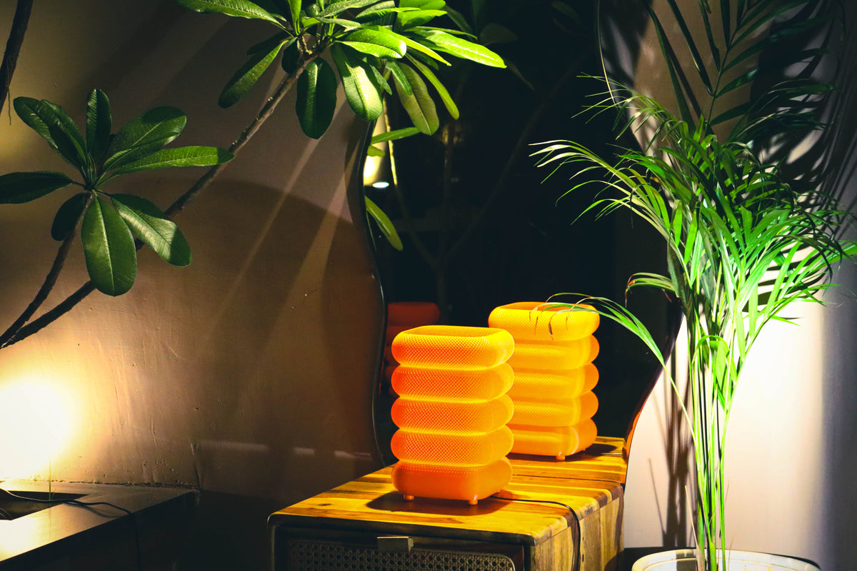 Stacked square lamps with mesh texture, warm orange glow, styled with plant
