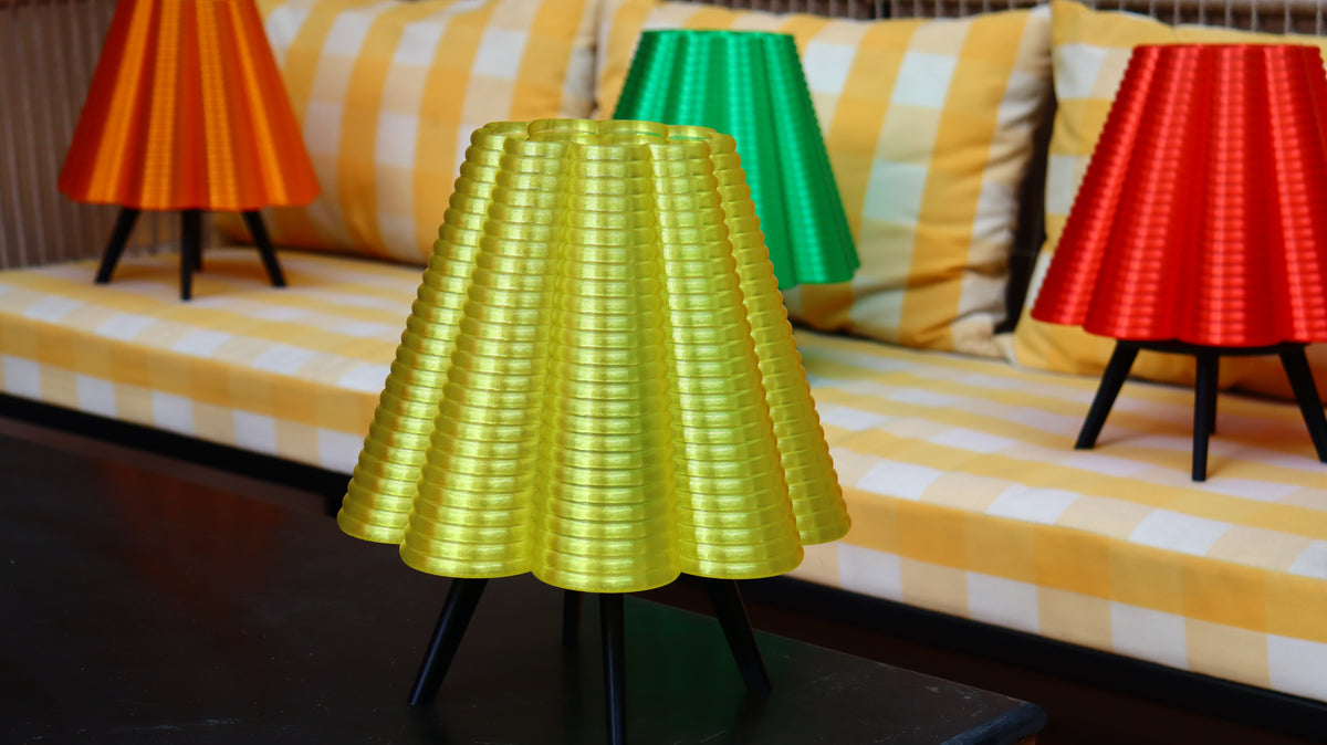 Yellow lamp on a black stand with colorful lamps in the background.