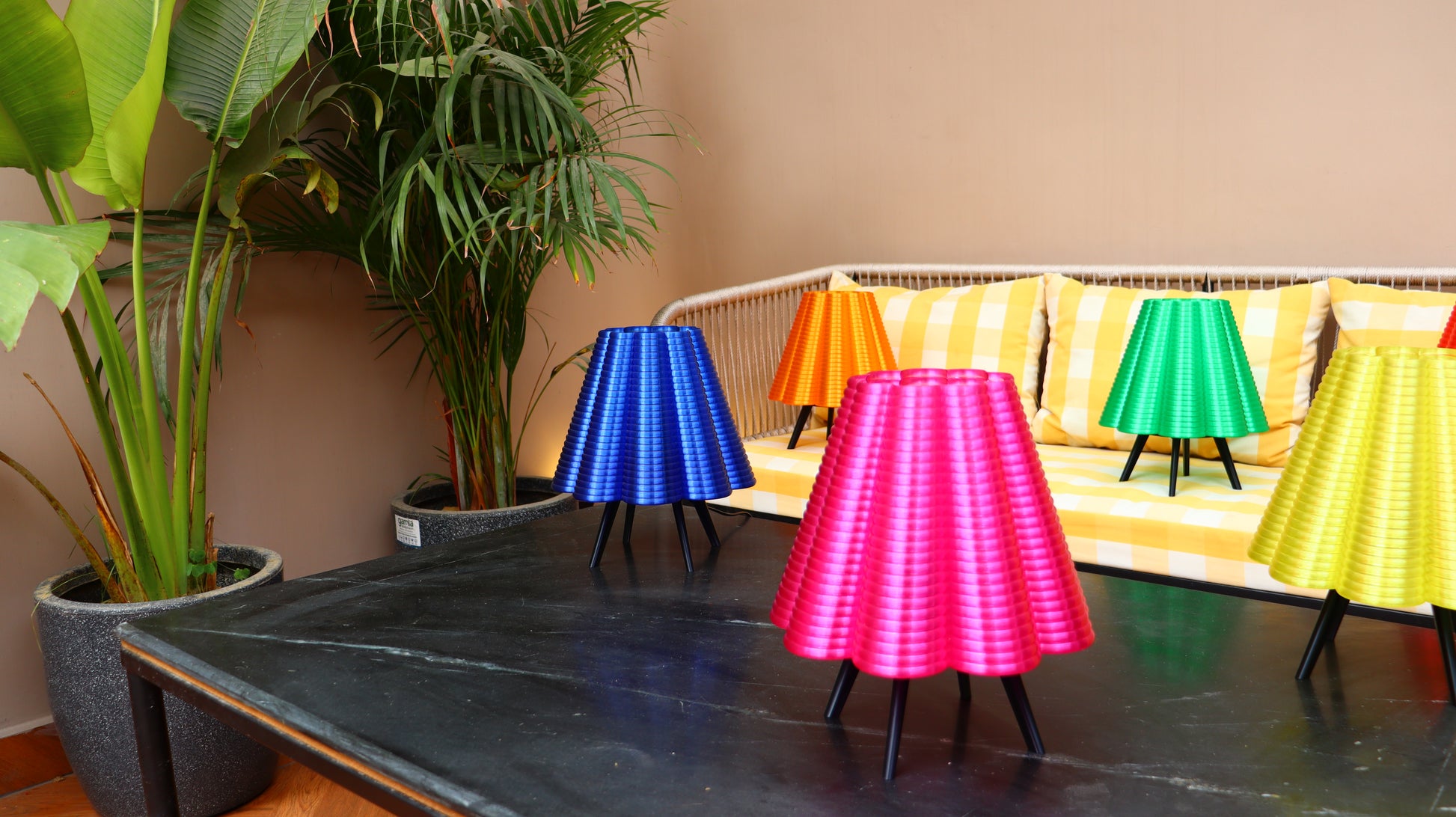 Fluted lampshade table lamp on slim black tripod legs, shown in blue, orange, yellow, and pink