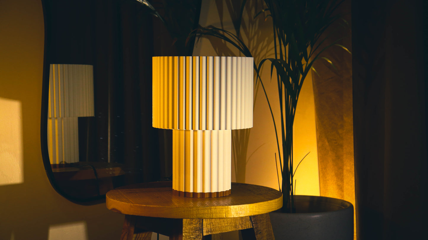 Two-tier fluted table lamp with pleated cylindrical shades on wooden side table