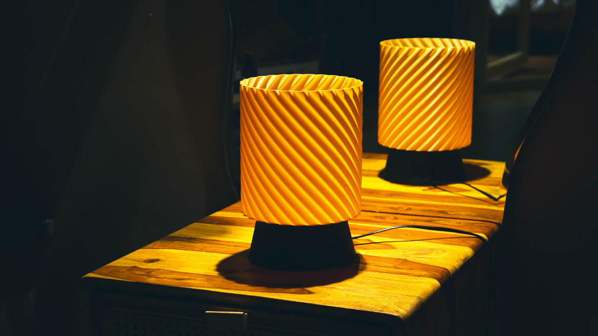 Viper Lamp - modern spiral-textured table lamp in amber glow, set on wooden surface
