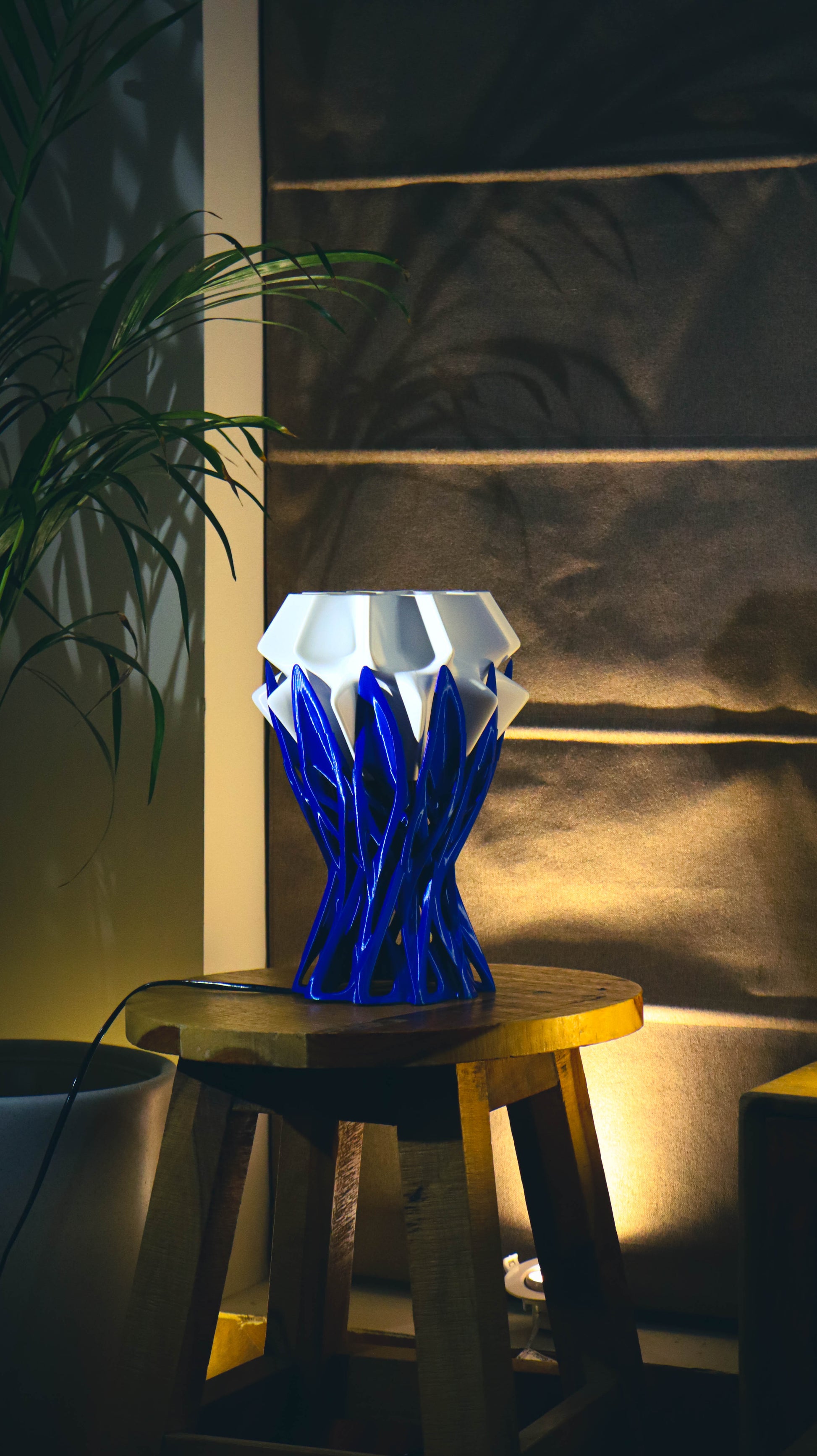 Blue crystalline spiked lamp shade on wooden stool with ambient warm lighting